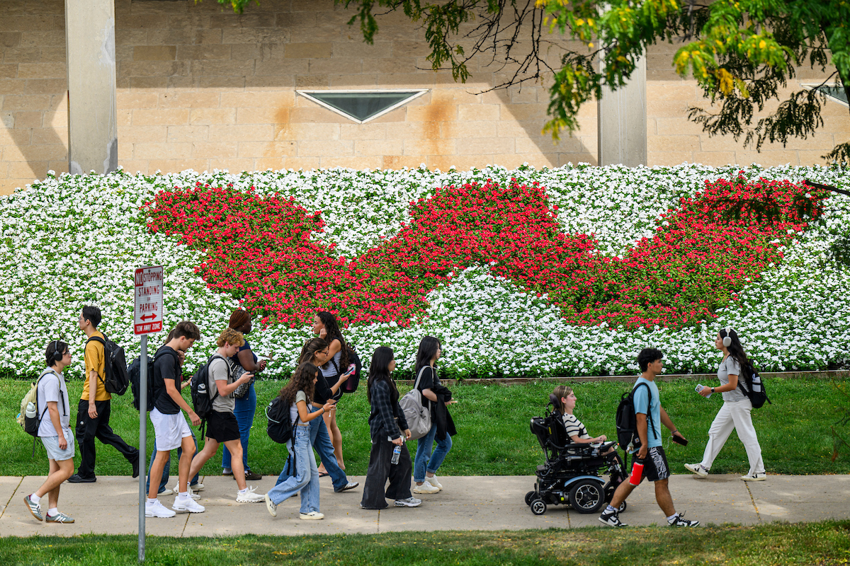 W shaped by flowers on UW-Madison campus with students walking by.